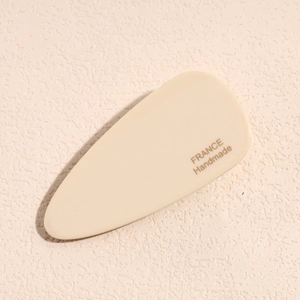 Close-up of cream handmade acetate hair clip with gold France lettering on textured base