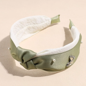 Close-up of green satin headband with pearls, butterfly metal charm and plush lining