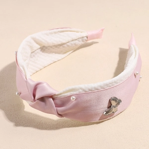 Detail view of pink satin headband with elegant knot, white pearls and butterfly crystal ornament