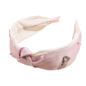 Pink satin headband with white waffle lining, knot detail, and pearl butterfly accent