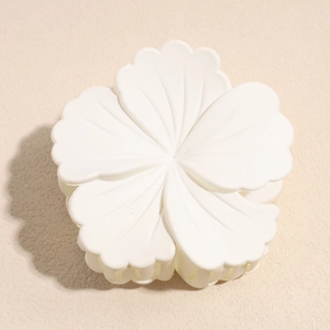 Detail view of a matte white flower hair claw clip with five-petal floral texture details