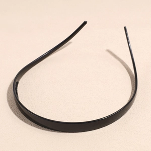 Detailopname van een smalle zwarte haarband met antislip tanden en een gladde glanzende afwerking