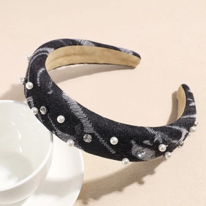 Detail of denim texture headband with pearls and rhinestones on a beige surface