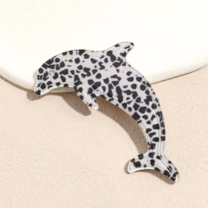 Macro detail of acetate dolphin hair clip featuring a black and white leopard pattern and rhinestone