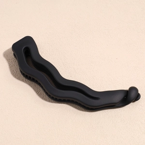 Détail d'une pince banane ondulée noire mate avec dents internes pour une tenue ferme