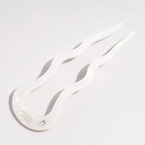 Detail of white U-shaped acetate hair pin with wave design and sparkling rhinestone
