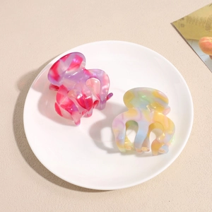 Colorful acetate marble claw clips for hair shown in a minimalist white ceramic tray