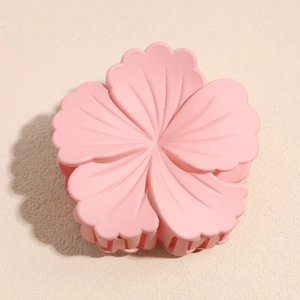 Detail of matte pink hibiscus flower hair claw clip with strong grip teeth for styling