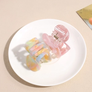 Colorful acetate claw hair clips with marble texture in a minimalist white porcelain tray