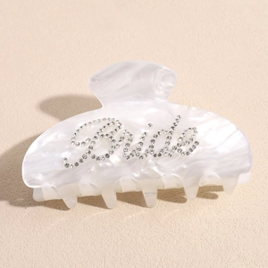 Dettaglio della scritta Bride in strass scintillanti sulla pinza per capelli bianca