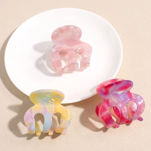 Three colorful marble pattern acetate hair claws set in a ceramic dish display