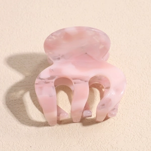 Detailed macro view of small pink marble acetate claw clip with smooth curved teeth