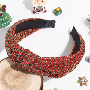 Detail of red and green glitter knot headband on a festive wooden prop