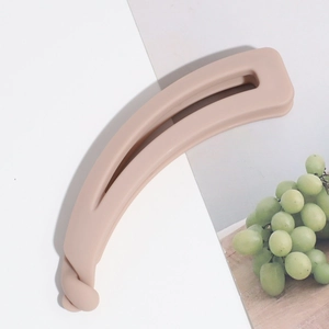 Détail d'une pince banane rose mat avec dents ondulées et mécanisme de verrouillage