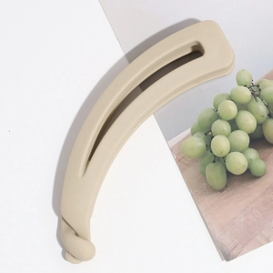 Détail de la pince banane beige mat au design ondulé minimaliste avec dents de maintien
