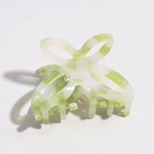 Detail view of small butterfly hair claw clip with white and green marble texture