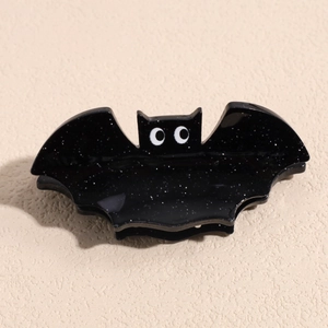 Macro shot of Halloween hair claw featuring a black glitter bat design with cartoon eyes