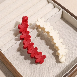 Barrettes bananes fleurs mates en rouge et beige présentées dans un écrin