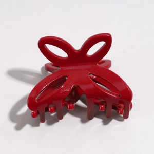 Detail view of a bright red butterfly hair claw clip with cutout design on white backdrop
