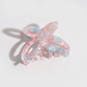 Close-up of butterfly hair claw with blue and pink marble texture in acetate finish