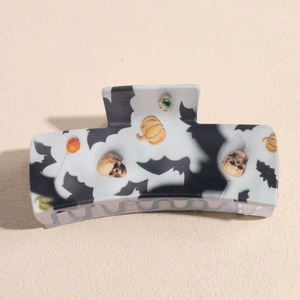 Detail of Halloween hair claw clip featuring pumpkins and bats on a rectangular acrylic base