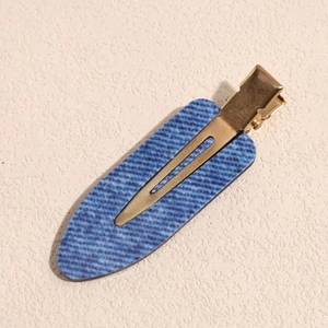 Close-up of a blue denim pattern hair clip with elegant gold metal duckbill base