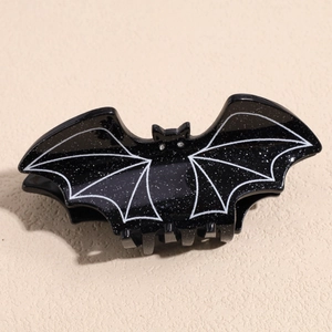 Close-up of black glitter bat hair claw with white wing details and rhinestone eyes
