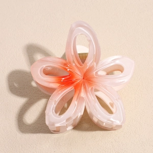 Détail macro d'une pince à cheveux fleur de frangipanier avec dégradé rose et orange