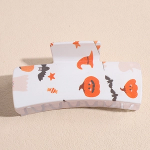 Macro detail of square hair claw clip featuring festive Halloween pumpkin and ghost patterns