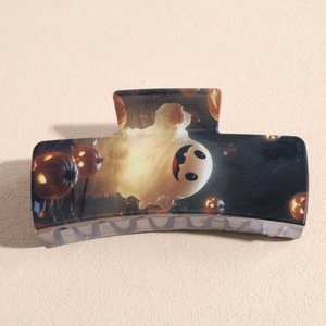 Close-up of black square hair claw clip featuring festive ghost and pumpkin patterns