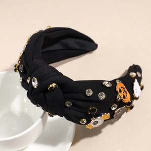 Détail d'un serre-tête noué d'Halloween avec strass, citrouilles et breloques fantômes