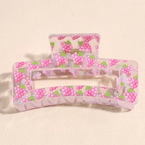 Detail of pink transparent square hair claw clip with grape pattern and gold spring