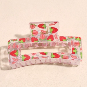 Detail of transparent square hair claw clip with red strawberry prints and gold spring