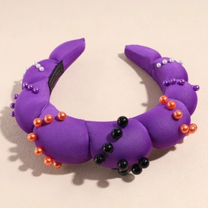 Detailed close-up of purple padded pearl headband with orange and white accents