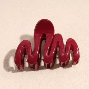 Macro shot of wavy burgundy hair claw clip with glossy finish and metal spring detail