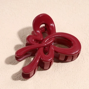 Close-up of a glossy dark red bow-shaped hair claw clip with a sleek resin finish
