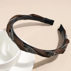 Détail du serre-tête torsadé en satin marron avec strass et dents antidérapantes noires