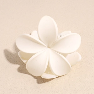 Close-up of matte white flower hair claw clip with elegant five-petal frangipani design