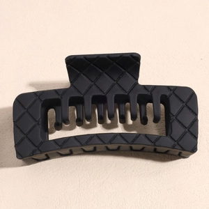 Macro detail of large black matte claw clip featuring a classic quilted lattice pattern