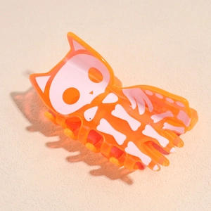 Détail de la pince à cheveux orange d'Halloween avec motif squelette de chat blanc