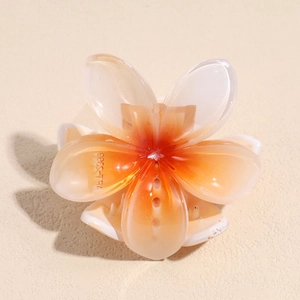 Detailed view of translucent resin plumeria flower hair claw clip with orange gradient