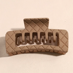 Detail shot of a matte brown rectangular hair claw clip with woven texture and strong teeth