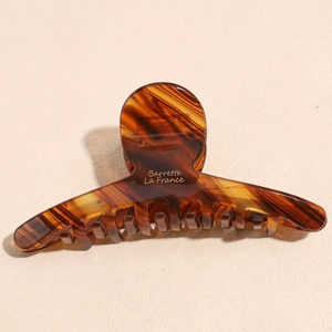 Detail of amber acetate hair claw clip featuring golden Barrette La France lettering