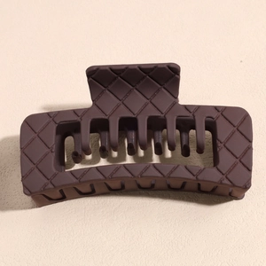 Macro detail of dark brown matte square claw clip showing its woven diamond pattern texture