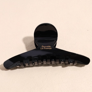 Close-up of black glossy hair claw clip with golden Barrette La France lettering