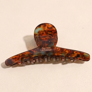 Detailed macro shot of vintage amber acetate hair claw clip with golden text engraving