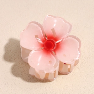 Détail de la pince à cheveux en forme de fleur avec dégradé de rose et texture lisse