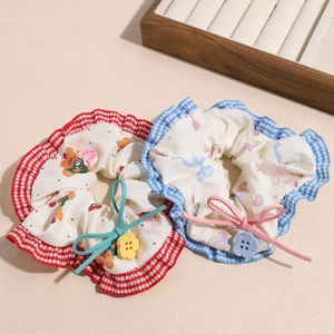 Sweet fabric scrunchies with cherry patterns, bow knots and flower buttons on light background