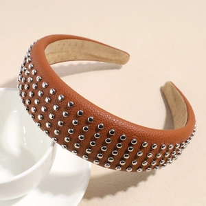 Detail of a brown leather headband featuring silver metallic studs and sponge filling texture