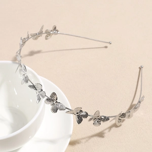 Détail du serre-tête argenté orné de papillons délicats posé sur une tasse blanche